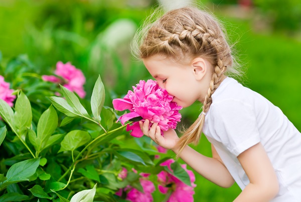 Дівчинка нюхає квіти.