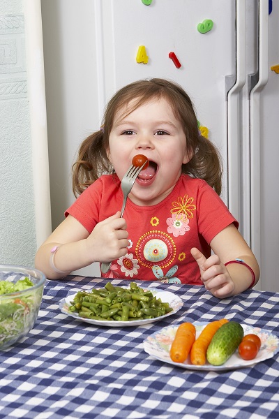 Девочка ест овощи - фото